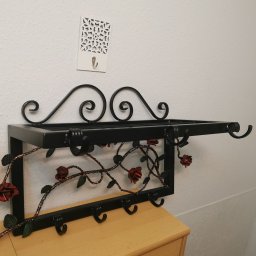 Kuty wieszak metalowy z kwietnymi ornamentami. 