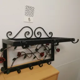 Kuty wieszak metalowy z kwietnymi ornamentami.