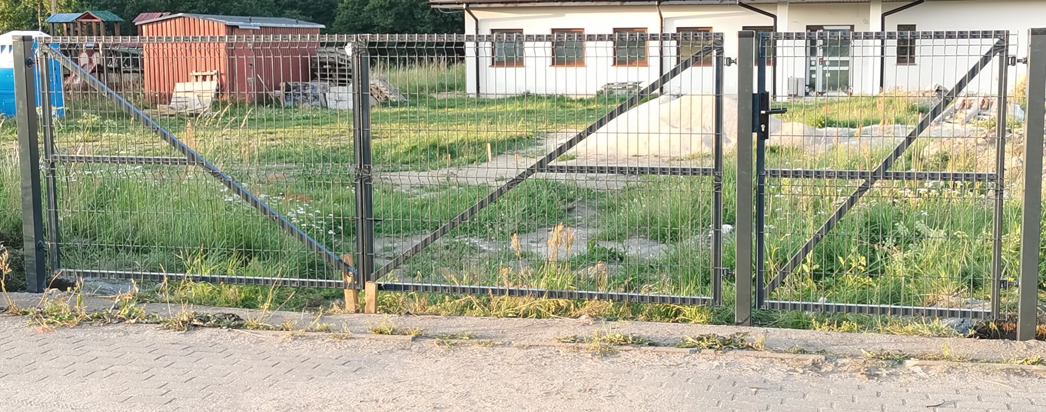 Brama skrzydłowa z wypełnieniem panelowym komponująca się z ogrodzeniem.