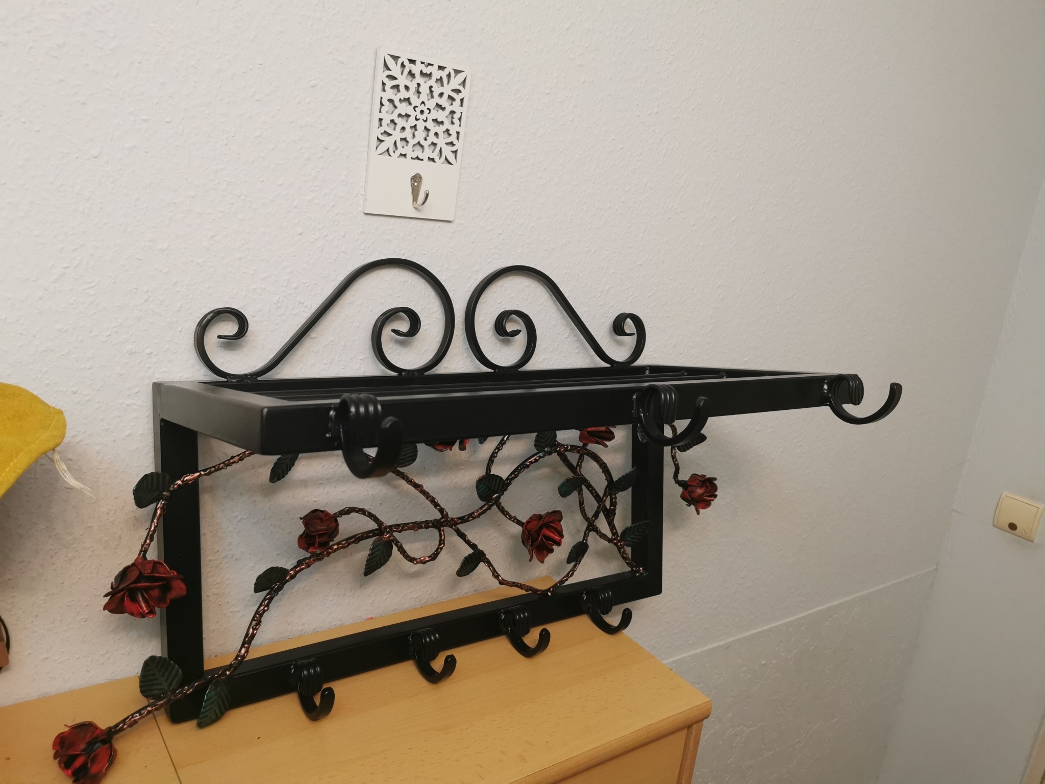 Kuty wieszak metalowy z kwietnymi ornamentami.