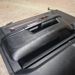 Usługi Tapicerskie Sebastian Kasperski - Tapicerowany, czarny panel drzwi samochodowych z drewnianym akcentem, leżący na szorstkiej powierzchni w warsztacie.