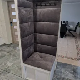 Szary, tapicerowany narożnik z wieszakami w przedpokoju, widok z boku, marmurowa podłoga.