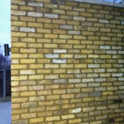 Met -Bud - Świeżo wymurowana ściana z żółtej cegły, widoczny fragment budynku w tle, pochmurne niebo.