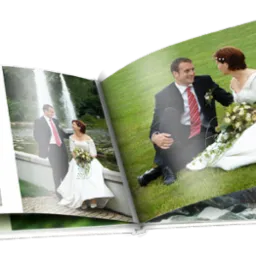 Otwarty album ślubny prezentujący zdjęcia pary młodej: na huśtawce, przy fontannie i siedzących na trawie.