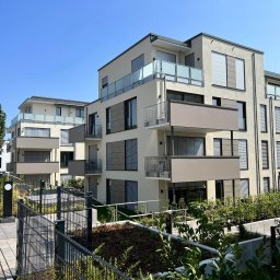 STEEL WINGS MARKUS REISER - Nowoczesne budynki wielorodzinne z balkonami z balustradami ze szkła i metalu, ogrodzone panelowym ogrodzeniem w kolorze antracytowym.