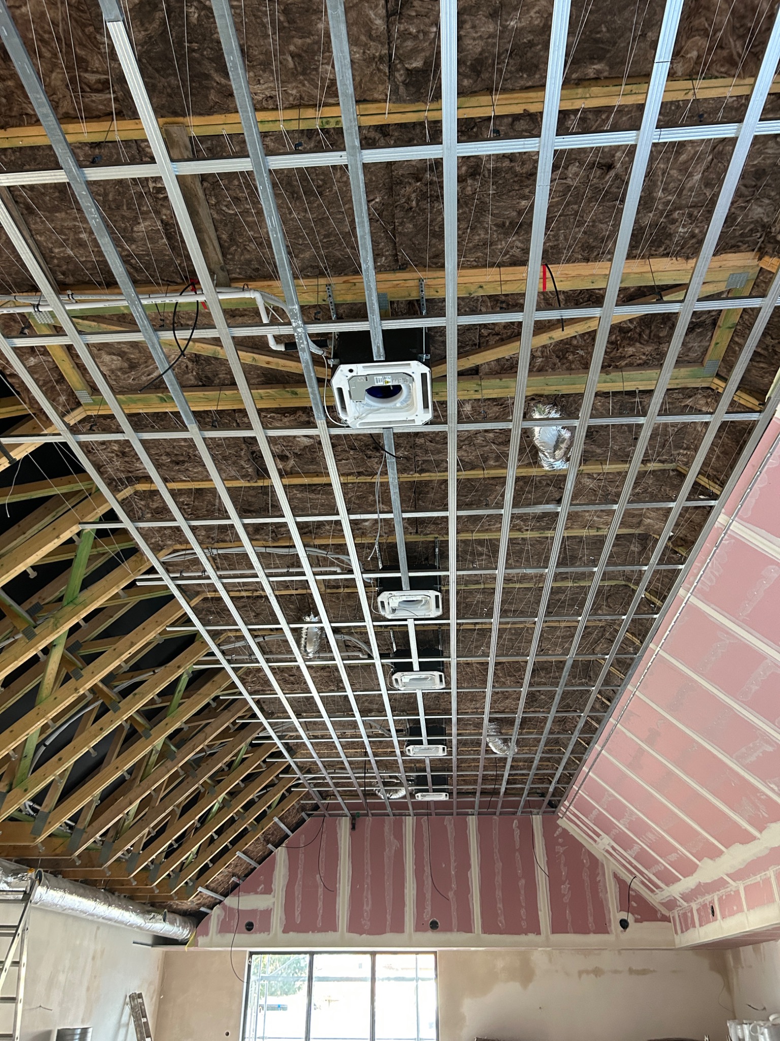 Montaż klimatyzacji kasetonowej w domu na etapie wykończenia sufitu podwieszanego, widoczne rury wentylacyjne i izolacja stropu.