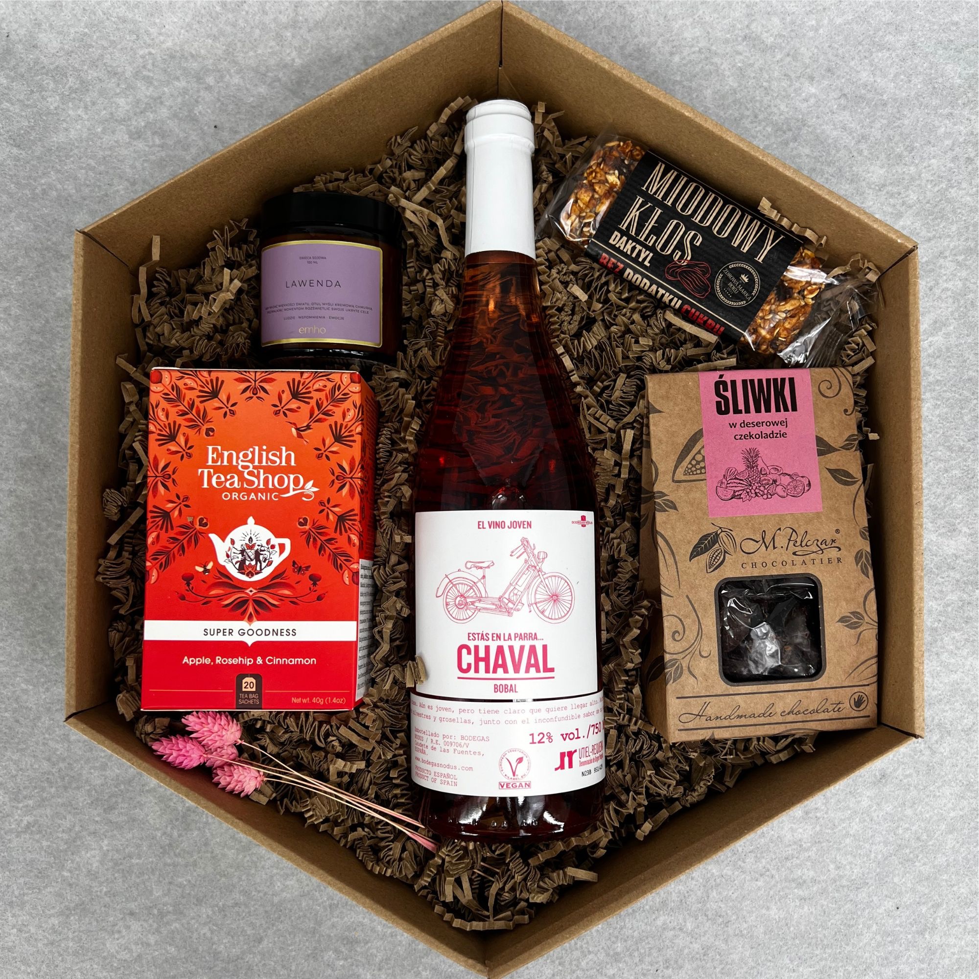 Zestaw upominkowy w tekturowym pudełku wypełnionym papierowym siankiem, zawierający wino różowe z etykietą z rysunkiem roweru, herbatę English Tea Shop o smaku jabłka, dzikiej róży i cynamonu...