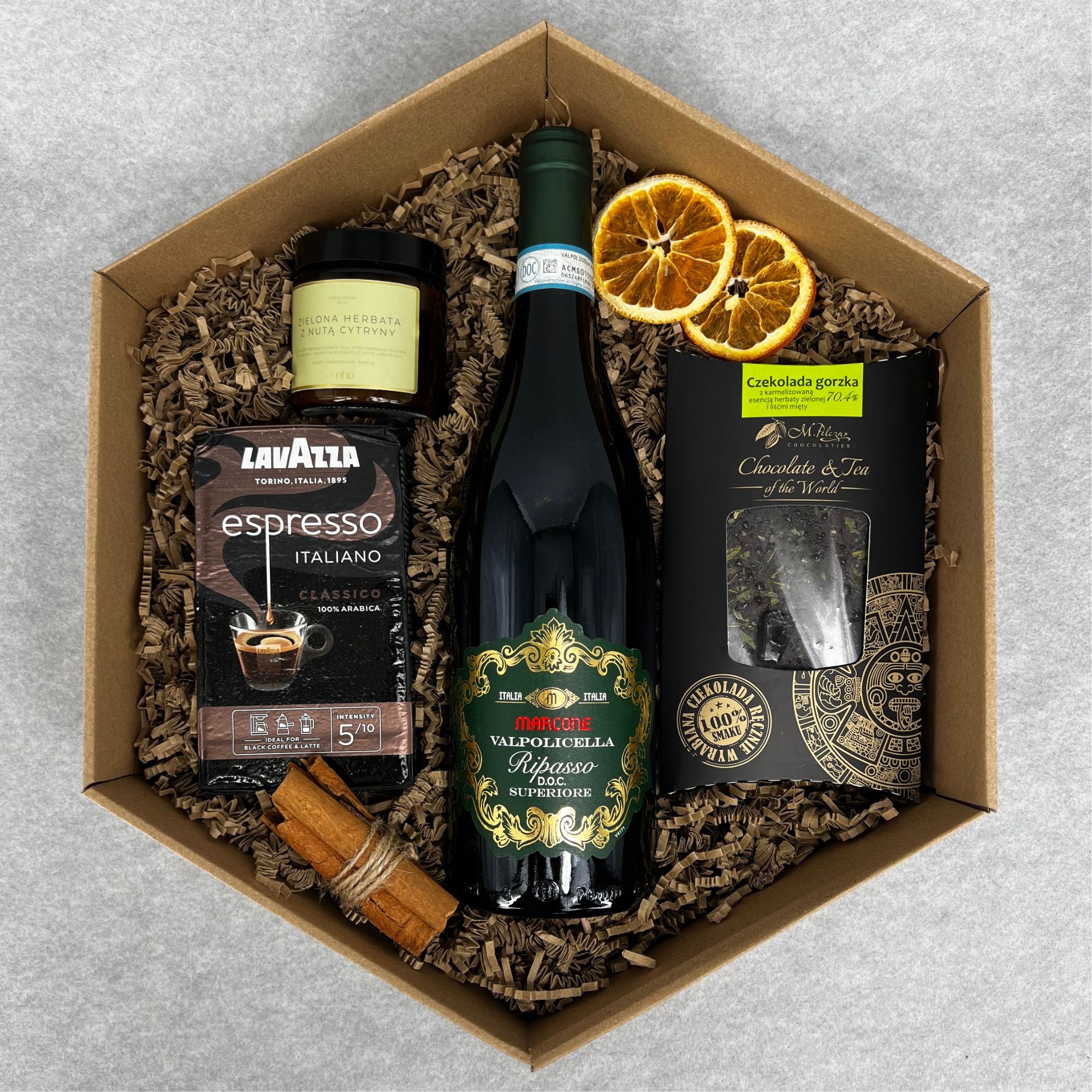 Elegancki zestaw upominkowy w kartonowym pudełku wypełnionym papierowym siankiem, zawierający butelkę wina Valpolicella Ripasso, paczkę kawy Lavazza Espresso Italiano, słoik zielonej herbaty z nutą...