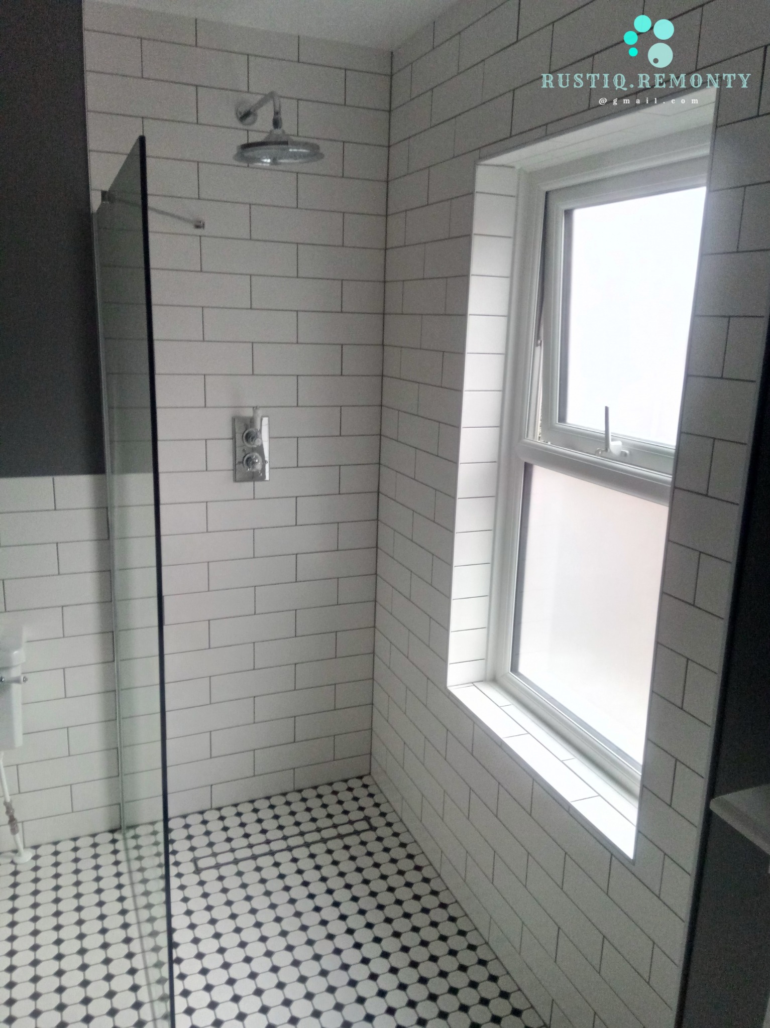 Wykończona łazienka z białymi płytkami imitującymi cegłę, kabiną prysznicową ze szklaną ścianą, deszczownicą i podłogą w czarno-białe kropki, oświetlona naturalnym światłem z okna.
