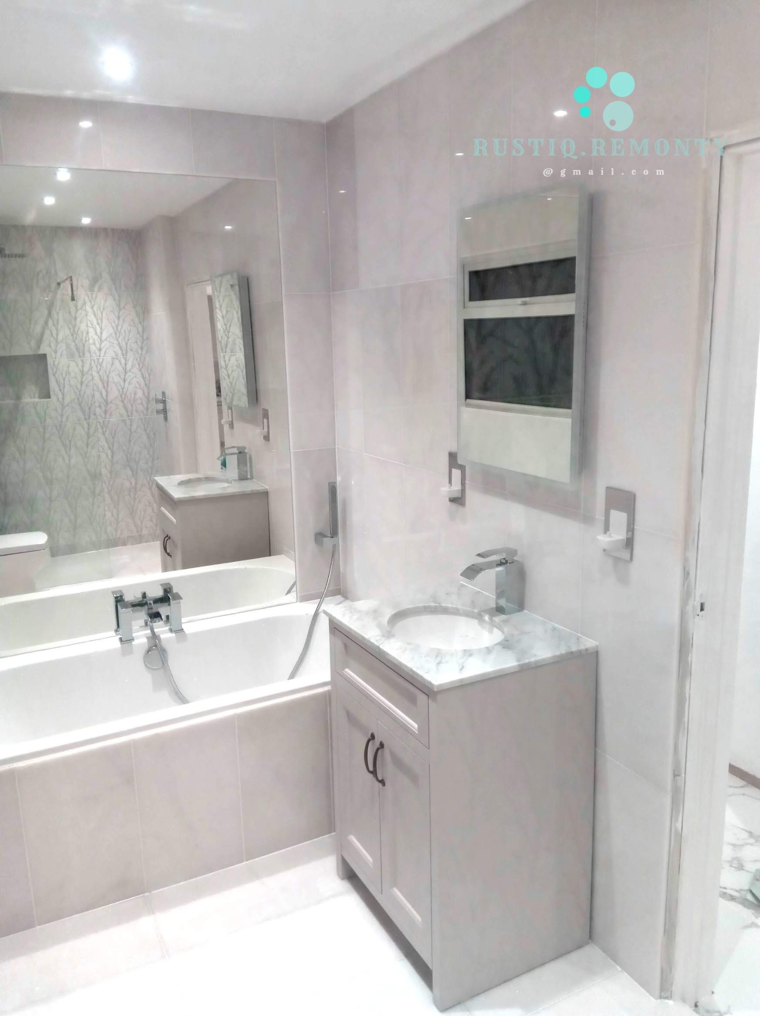 Wykończona łazienka w Barczewie z wanną, umywalką z szafką i dużym lustrem, utrzymana w jasnej kolorystyce z marmurowym blatem umywalki.