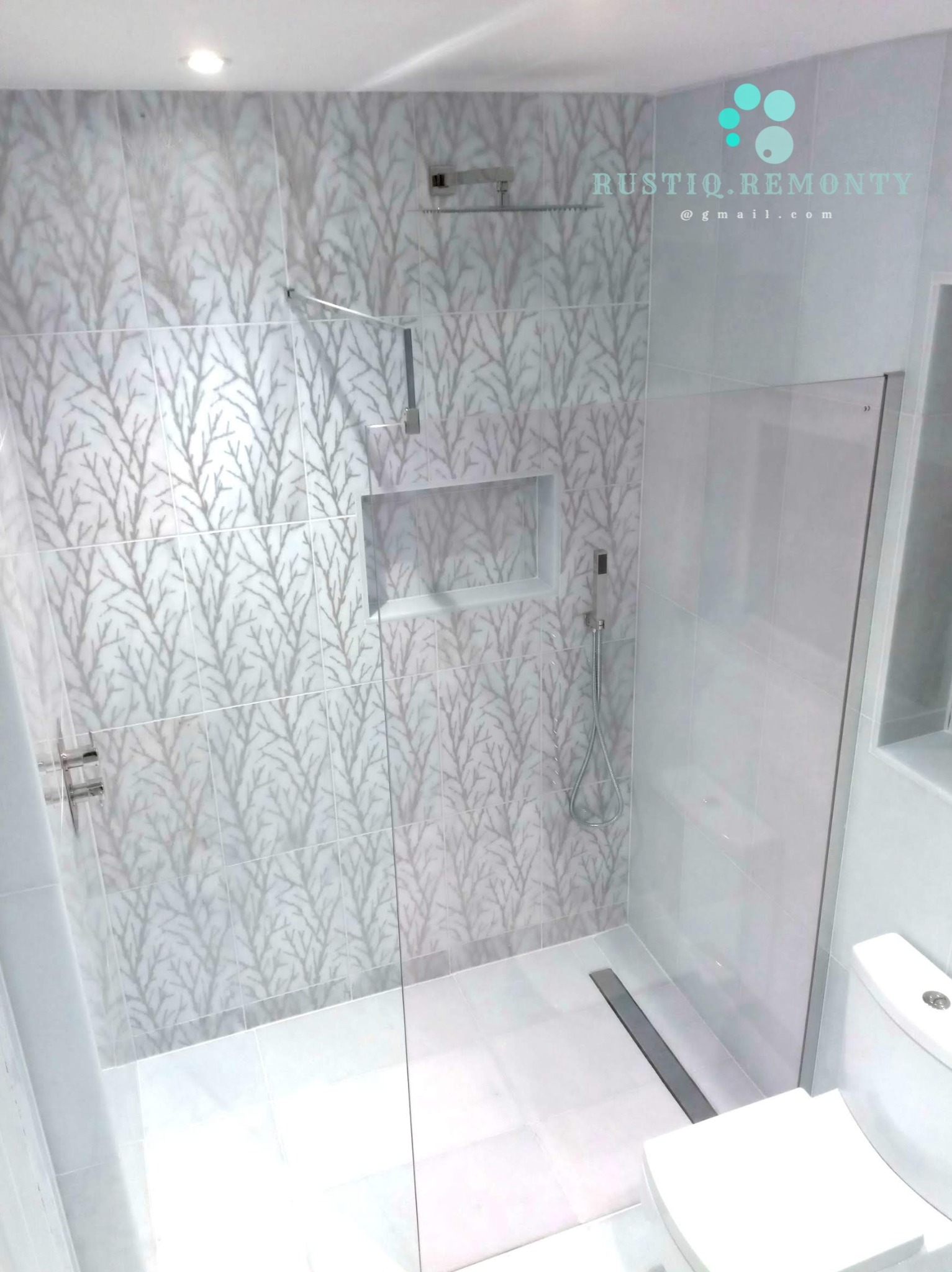 Nowoczesna łazienka z kabiną typu walk-in, wykończona białymi płytkami z subtelnym wzorem drzewnym, z wnęką w ścianie i odpływem liniowym w podłodze.