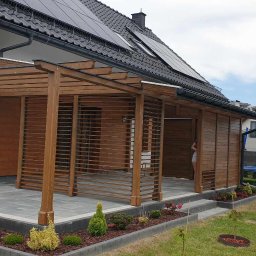 Woodesigne - Drewniana konstrukcja z żaluzjami na tarasie domu jednorodzinnego, widok na ogród z trampoliną w tle.