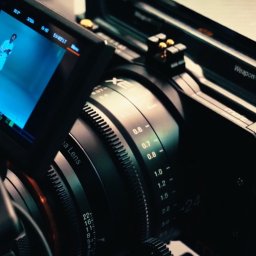 HOLE SP. Z O. O. - Profesjonalna kamera filmowa z widocznym ekranem podglądowym, na którym widoczna jest postać w białym stroju. Sprzęt używany przez firmy z Gliwic.