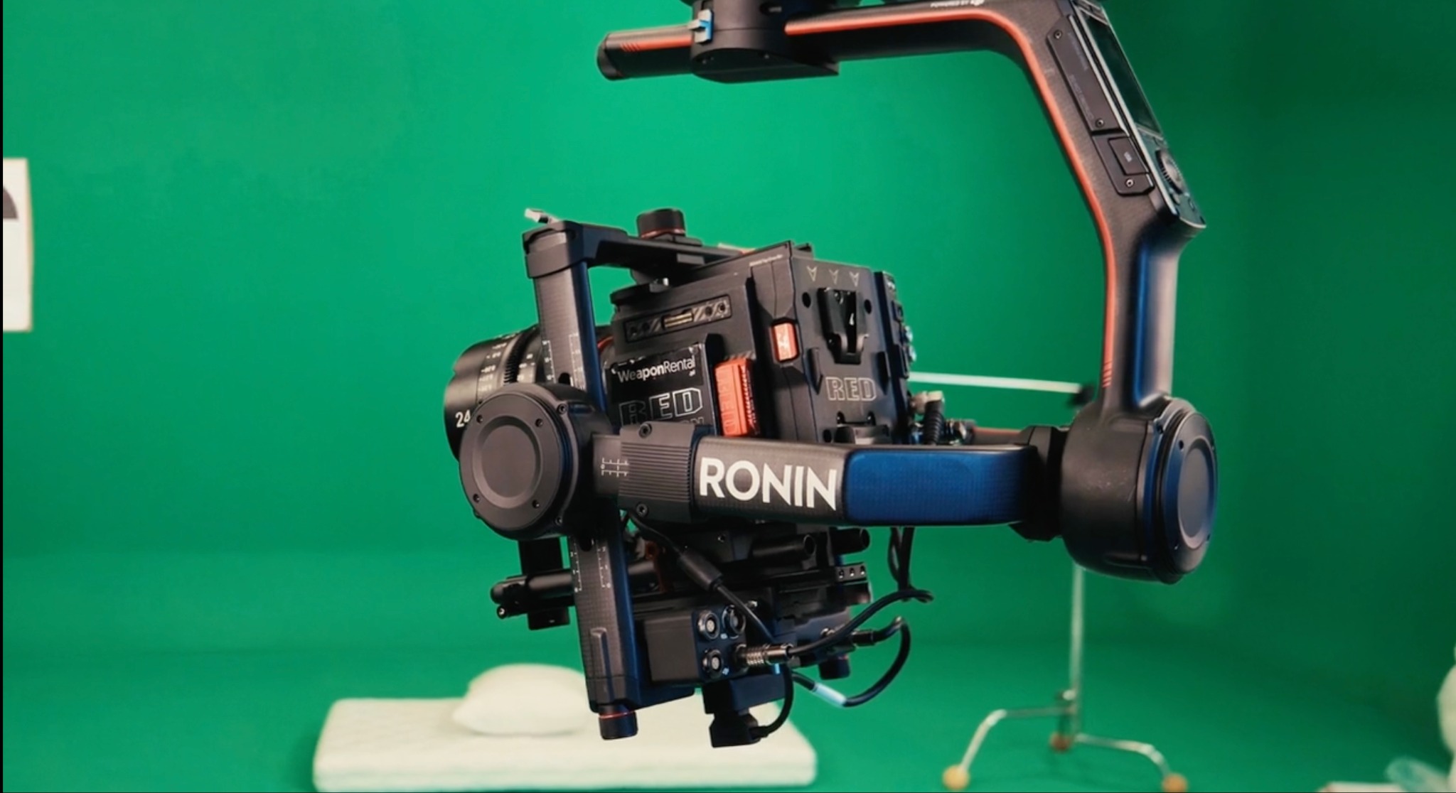 Profesjonalna kamera RED zamontowana na stabilizatorze Ronin, ustawiona na tle zielonego ekranu w studio filmowym.