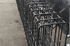 Szkielet konstrukcji żelbetowej z ułożonych prętów zbrojeniowych, widoczne zagięcia i wiązania drutem, szary beton w tle.