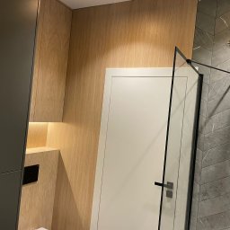 ANTEX - Nowoczesna łazienka z drewnianymi panelami, szarą mozaiką w jodełkę pod prysznicem z deszczownicą i minimalistyczną kabiną prysznicową z czarnymi profilami.