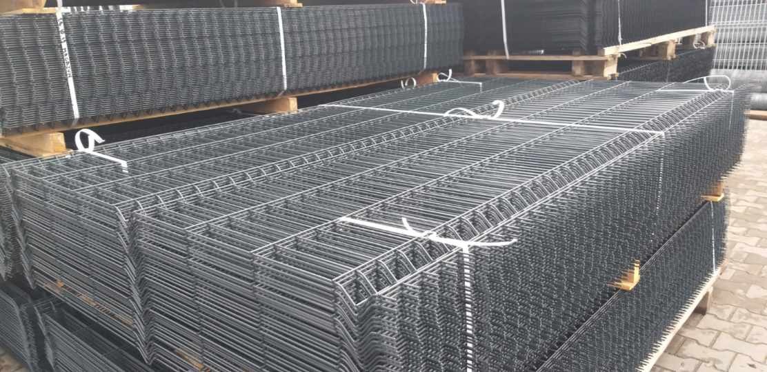 Stosy paneli ogrodzeniowych zgrzewanych, zabezpieczonych białym sznurkiem, ułożone na paletach w Olszewce, gotowe do transportu.