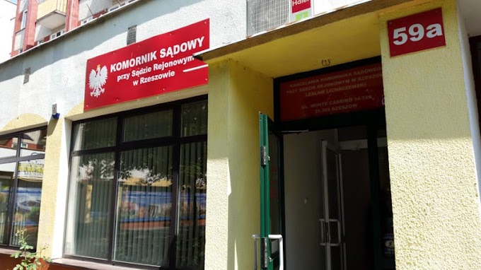 Fasada budynku z szyldem 'Komornik Sądowy przy Sądzie Rejonowym w Rzeszowie' i adresem 59a, widoczne okna z żaluzjami i wejście do kancelarii.