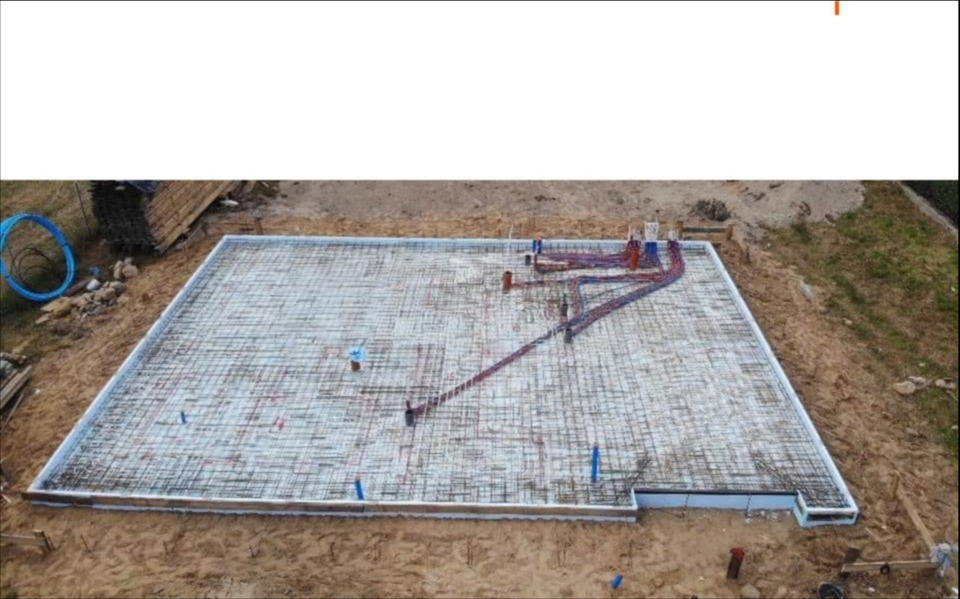Zbrojenie płyty fundamentowej z instalacją ogrzewania podłogowego, widok z góry. Przygotowanie do wylania betonu. Izolacja termiczna z białego styropianu.