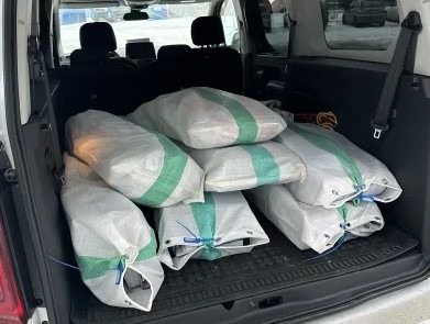 Bagażnik samochodu wypełniony workami z dokumentami przeznaczonymi do zniszczenia, zabezpieczonymi niebieskim sznurkiem.