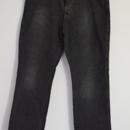 UNETI Leszek Janczalik - Czarne jeansy Wrangler, widoczne na wieszaku, z przetarciami i metalowymi elementami, na białym tle.