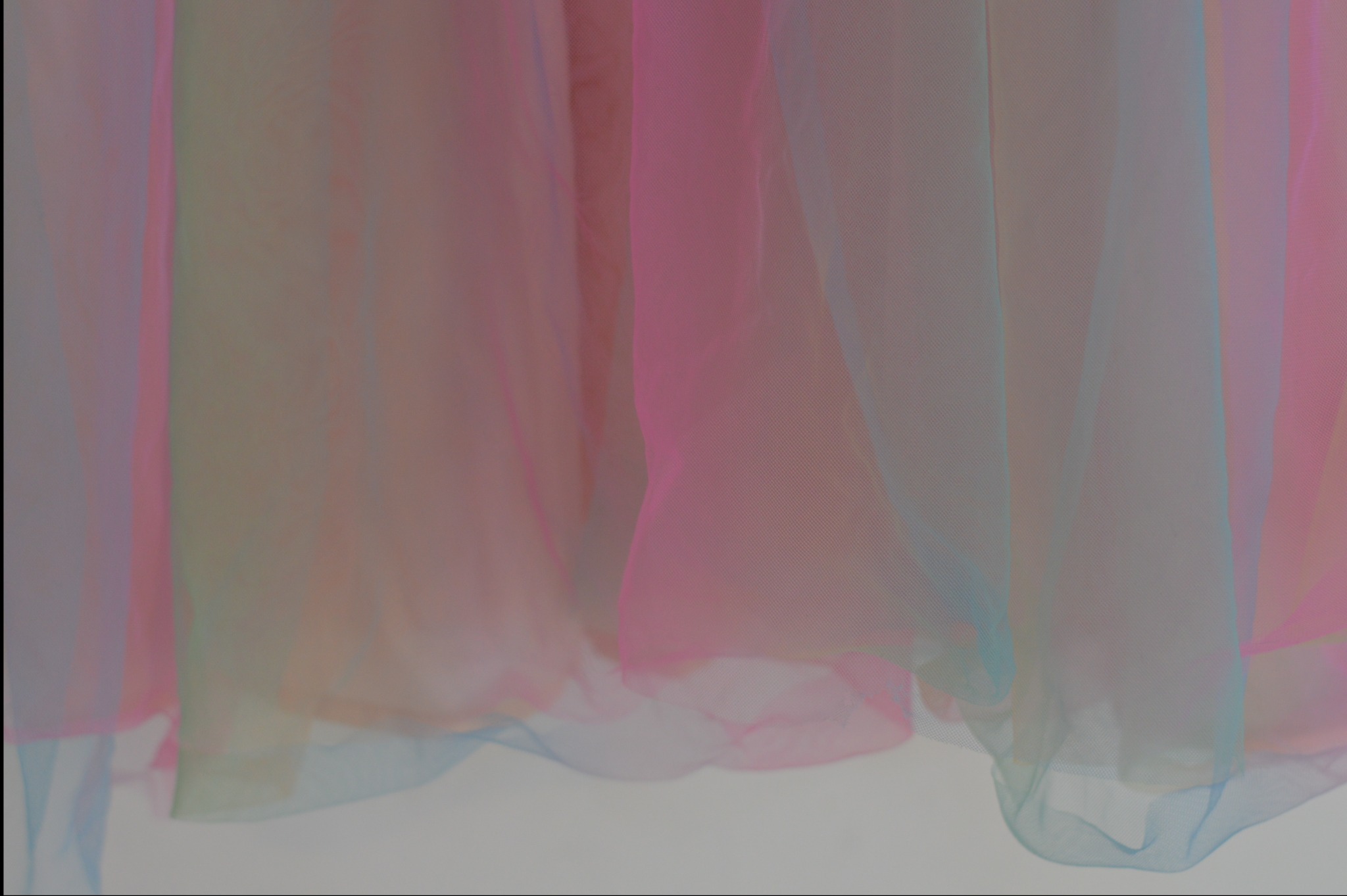 Delikatna, półprzezroczysta tkanina w odcieniach różu, błękitu i beżu, tworząca miękkie fałdy.