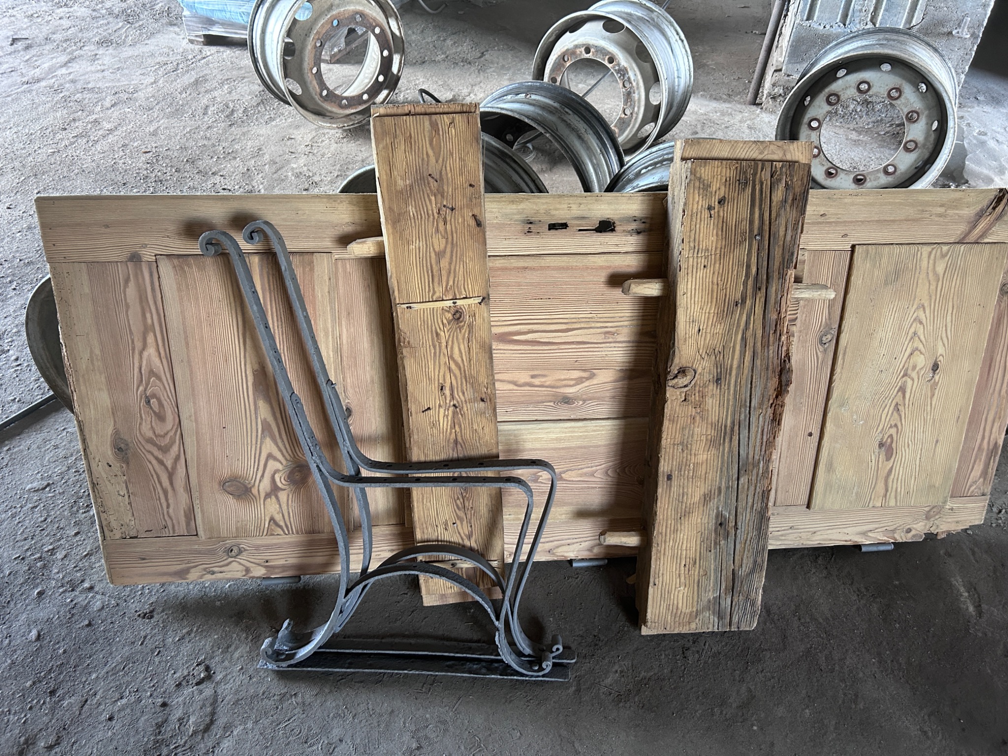 Drewniane panele i metalowy stelaż krzesła na tle betonowej podłogi i opon samochodowych.