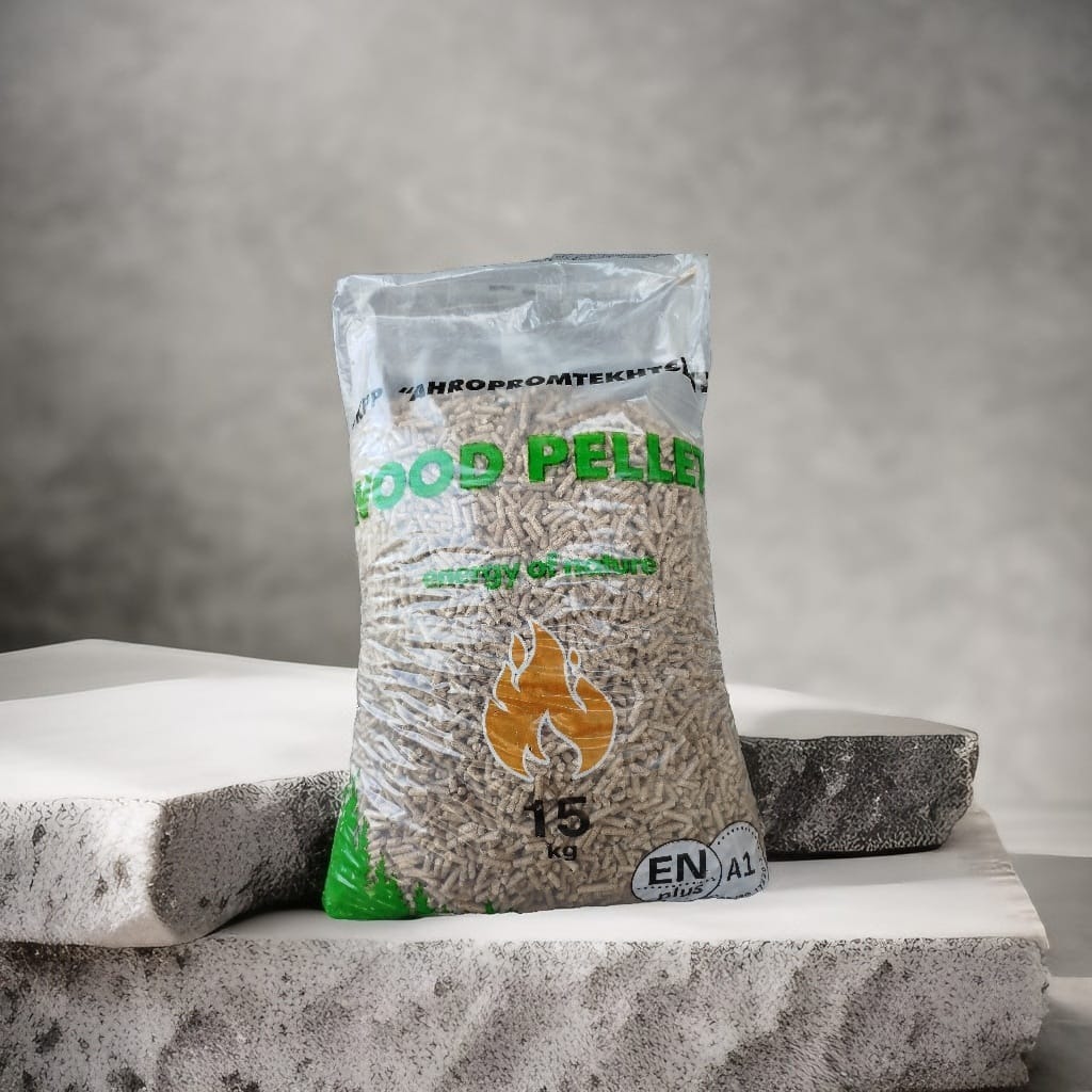 Worek przezroczysty z pelletem drzewnym o wadze 15 kg, z certyfikatem ENplus A1, ustawiony na białym, teksturowanym bloku betonowym na tle szarej ściany.