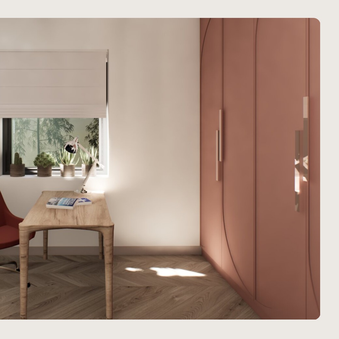 Wnętrze pokoju z biurkiem z jasnego drewna, lampką, książkami, roślinami w doniczkach na parapecie i dużą, różową szafą z ozdobnymi uchwytami.