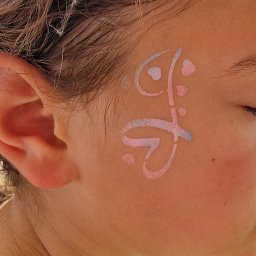 Bajkowe Animacje dla Dzieci Małopolska - Dziecięca twarz z delikatnym, pastelowym malunkiem w odcieniach różu i błękitu, przedstawiającym abstrakcyjny wzór. Zamknięte oko i jasne włosy dopełniają subtelny obraz.