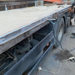 Car-Czyścik Daniel Ziaja - Prace spawalnicze na platformie ciężarówki, widoczne iskry, spawarka oraz częściowo sylwetka spawacza w rękawicach ochronnych.