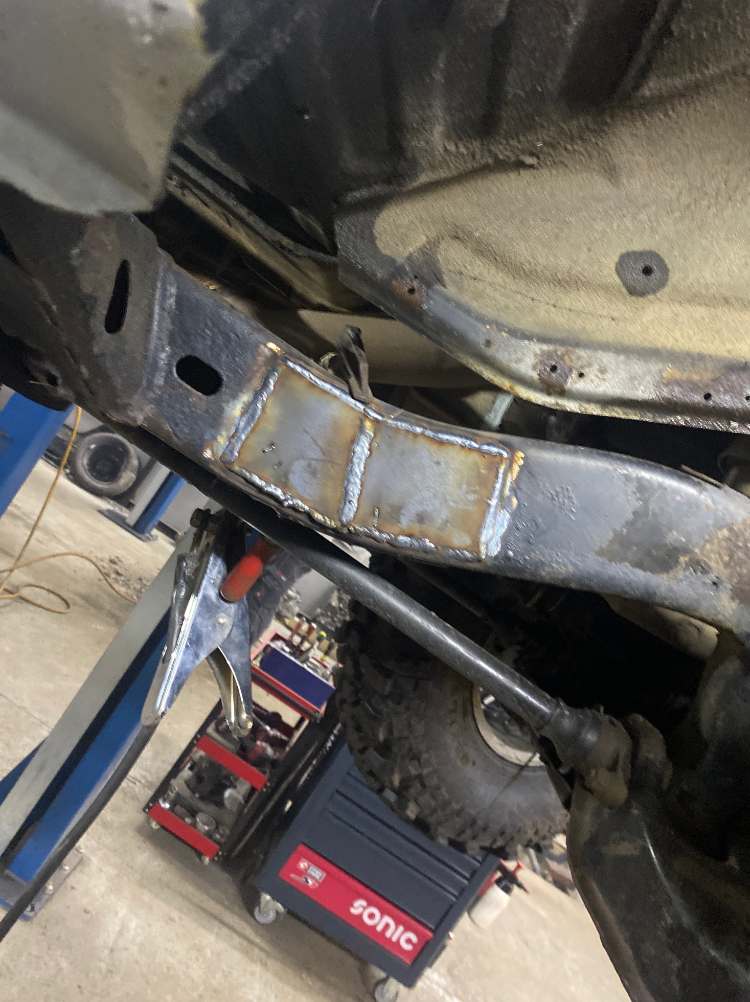 Wzmocnienie ramy samochodu terenowego poprzez wspawanie blachy, widoczne spawy, narzędzia i opona terenowa