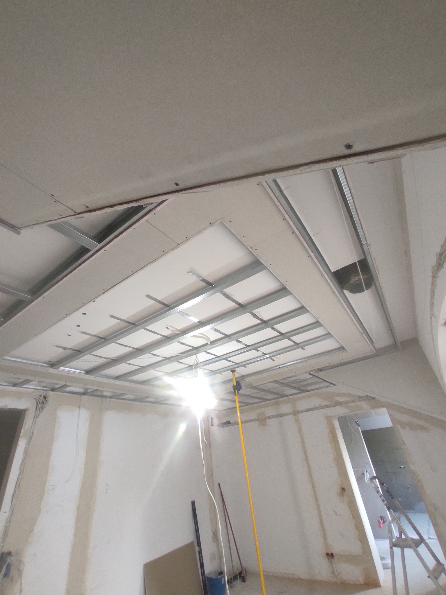 Sufit podwieszany z metalową konstrukcją w trakcie montażu w mieszkaniu w Warszawie, widoczne narzędzia i drabina.