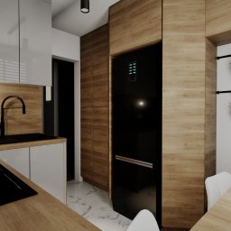 KORANTI Izabela Kornacka - Nowoczesna kuchnia z drewnianymi akcentami: zabudowa z lodówką, czarny zlew i płyta indukcyjna, białe szafki, zioła w doniczkach na ścianie.