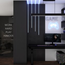 KORANTI Izabela Kornacka - Nowoczesny pokój gracza z czarnym biurkiem, neonami i ścianą z napisem 'Work hard, play harder'. Minimalistyczny design z akcentami gamingowymi.