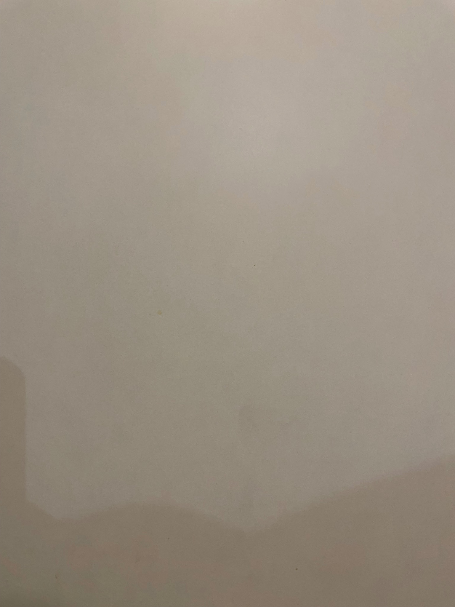 Beżowa, gładka powierzchnia z delikatnymi, nieregularnymi plamami i gradientem światła, sugerująca świeżo pomalowaną ścianę lub inne wykończenie wnętrza.