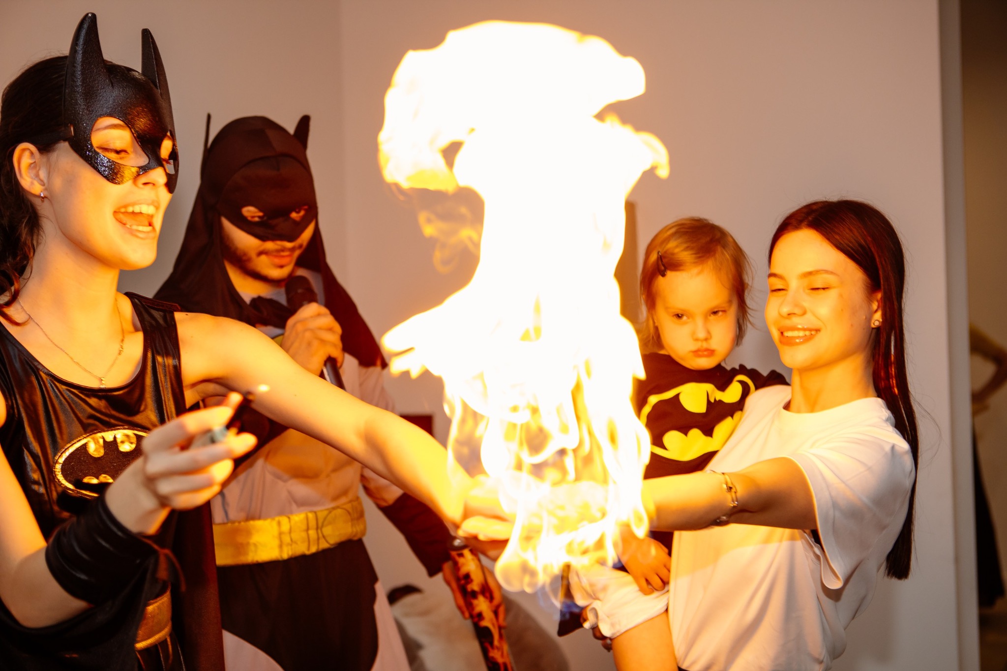 Animatorzy w strojach Batmana prezentują pokaz ognia dziecku na rękach. Impreza urodzinowa z atrakcjami dla dzieci, efekty specjalne, ogień na dłoniach.