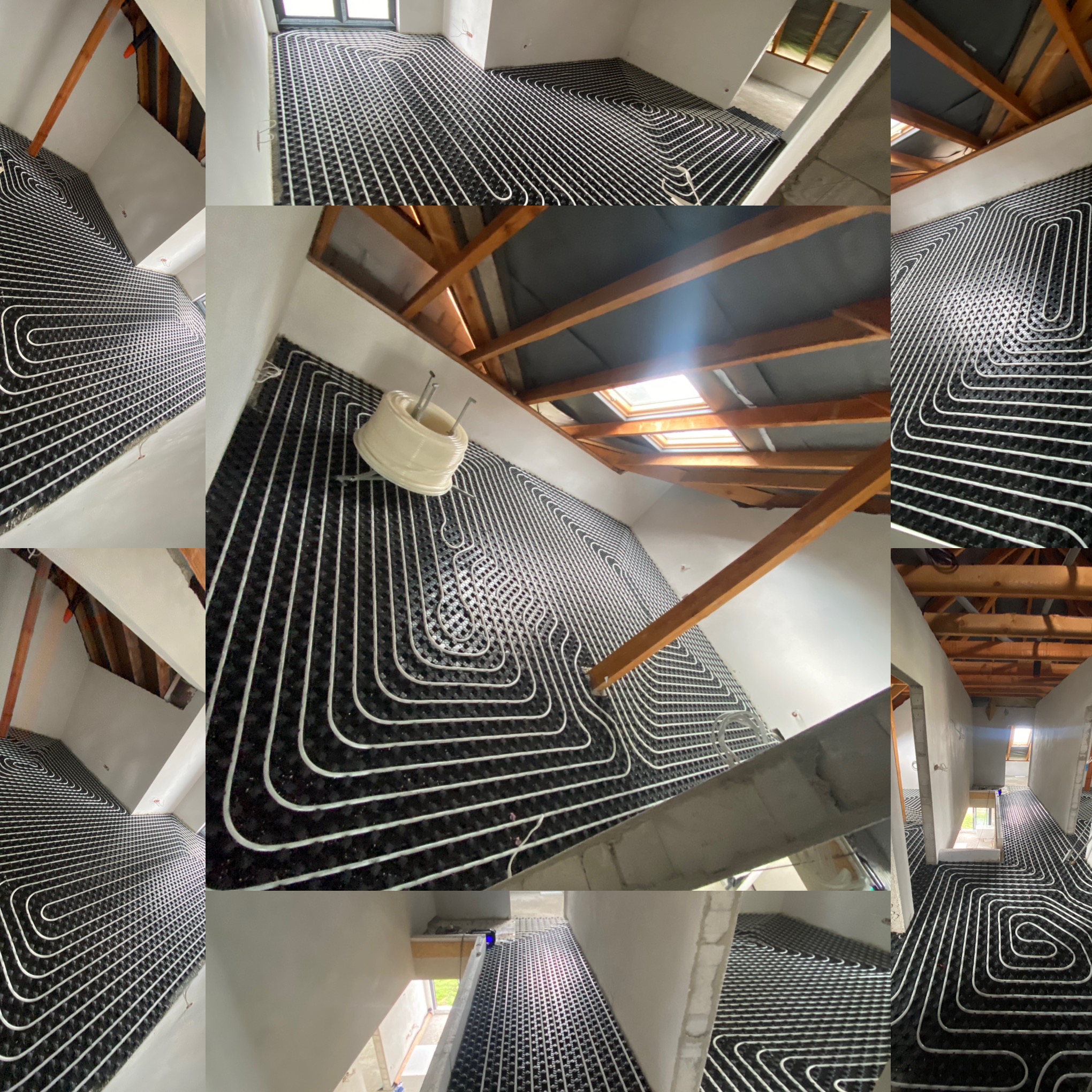 Rozłożone białe rury na czarnej macie w trakcie instalacji ogrzewania podłogowego w surowym pomieszczeniu z drewnianą konstrukcją dachu i oknem dachowym.