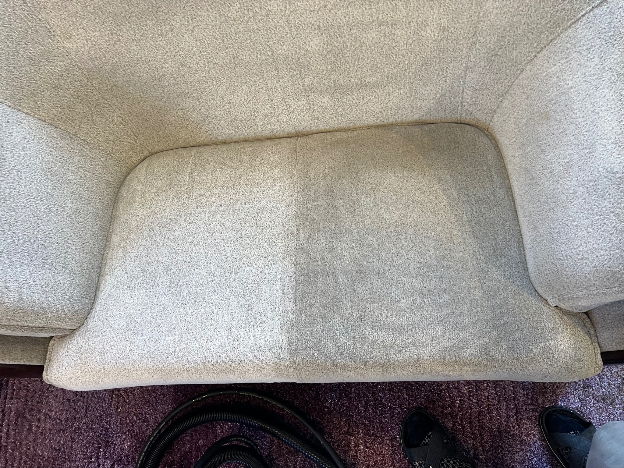 Beżowy fotel z widoczną różnicą w czystości tapicerki po prawej stronie, po lewej stronie tapicerka jest brudna. W tle fioletowy dywan i fragment węża ssącego.