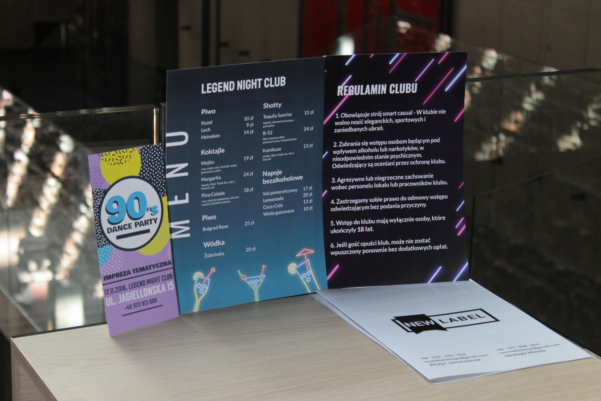 Zestaw drukowanych materiałów reklamowych dla klubu nocnego, w tym menu z drinkami, regulamin i wizytówka.