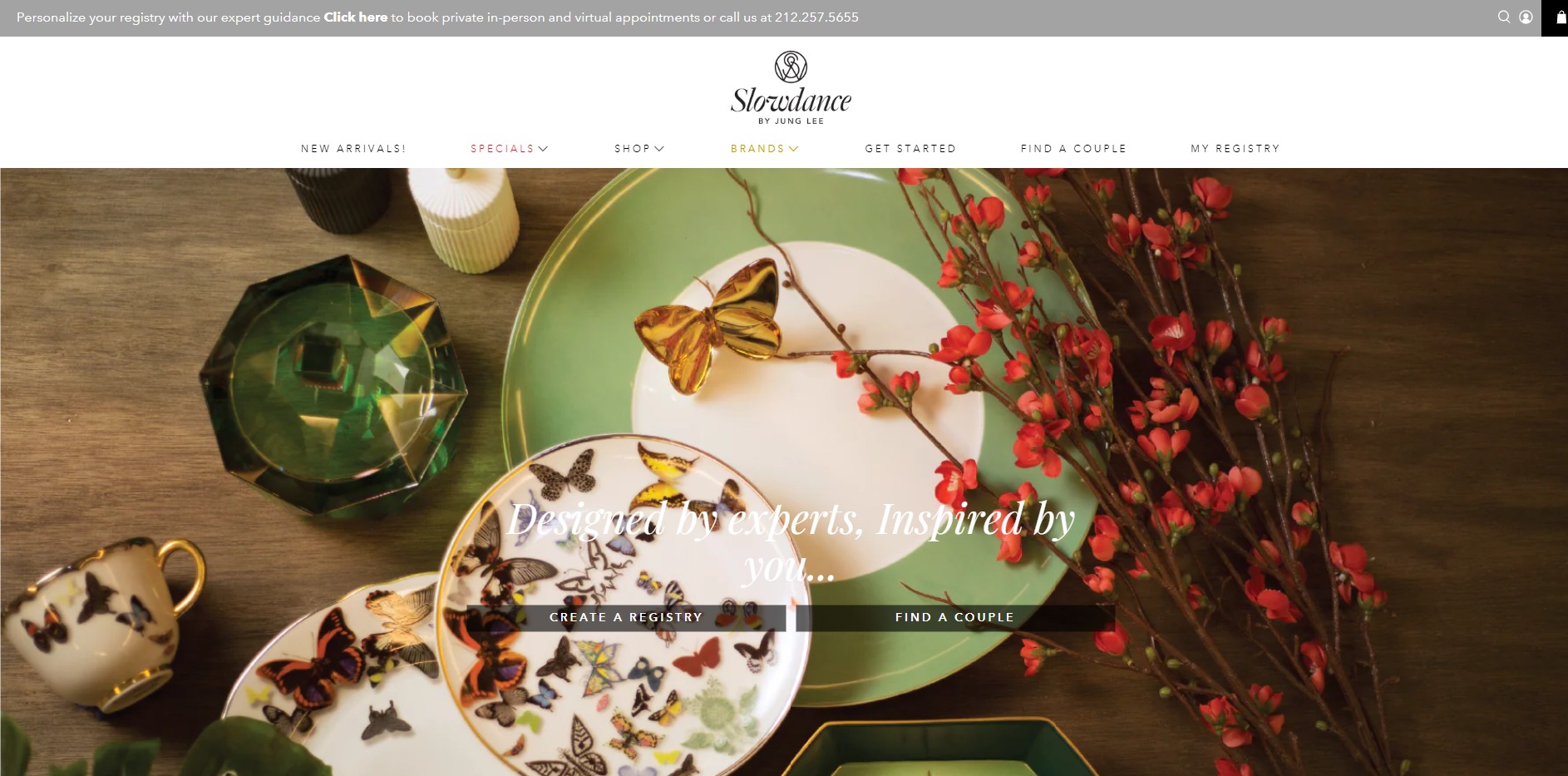 Elegancki zestaw porcelany z motywem motyli, złoty motyl na zielonym talerzu, kryształowy popielnik i gałązka z czerwonymi kwiatami na drewnianym stole