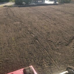 Szymon w Ogrodzie - Przygotowany grunt pod trawnik z widocznym urządzeniem do wyrównywania, w tle pergola i ozdobne trawy. Układanie trawy z rolki.