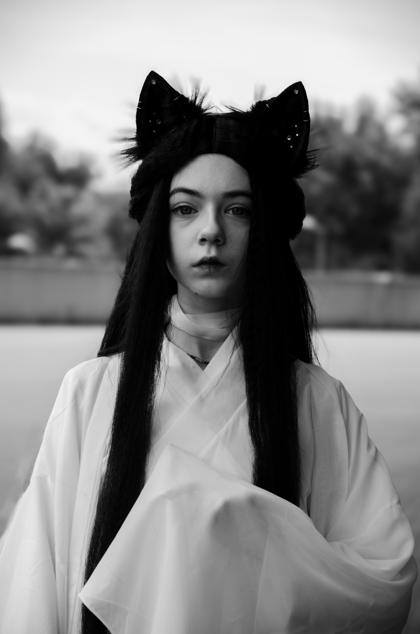 Portret młodej kobiety w kostiumie z uszami kota, czarno-białe zdjęcie z delikatnym rozmyciem tła.