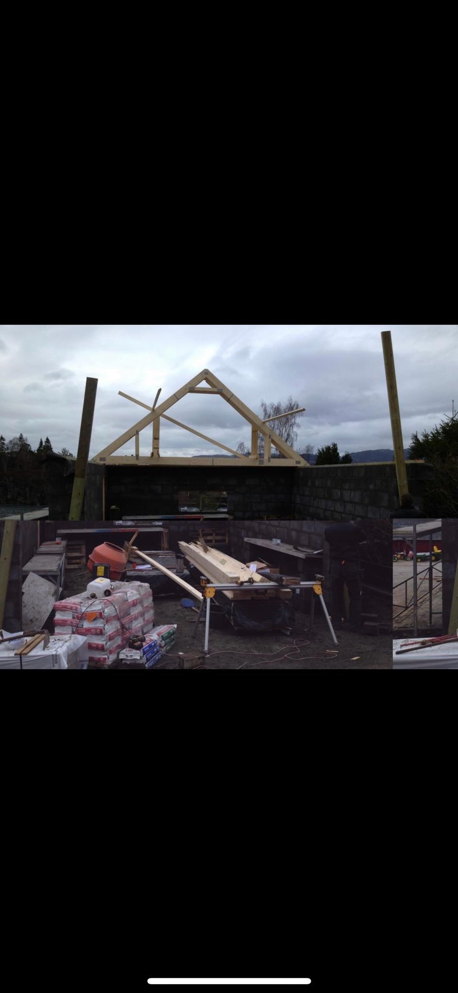 Wznoszenie drewnianej konstrukcji dachu na murowanych ścianach, widoczny betonowy mikser i materiały budowlane w workach, pochmurne niebo w tle.