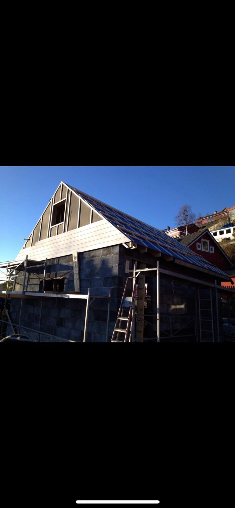 Budowa domu z bloczków w Gdyni na etapie wznoszenia ścian i konstrukcji dachu, widoczne rusztowania i drabina.