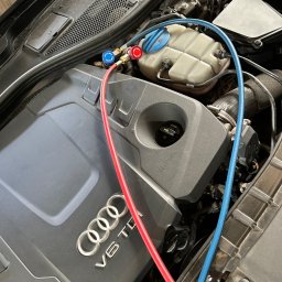 MOTOINVEST Paweł Nowrotek - Silnik Audi V6 TDI z podłączonymi przewodami serwisowymi klimatyzacji, widoczne złącza z manometrami w kolorach czerwonym i niebieskim.
