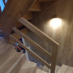 Firma ogolnobudowlana Jarzmik Kamil - Drewniane schody z jasnymi panelami, proste balustrady i widoczne zabawki dziecięce w tle.