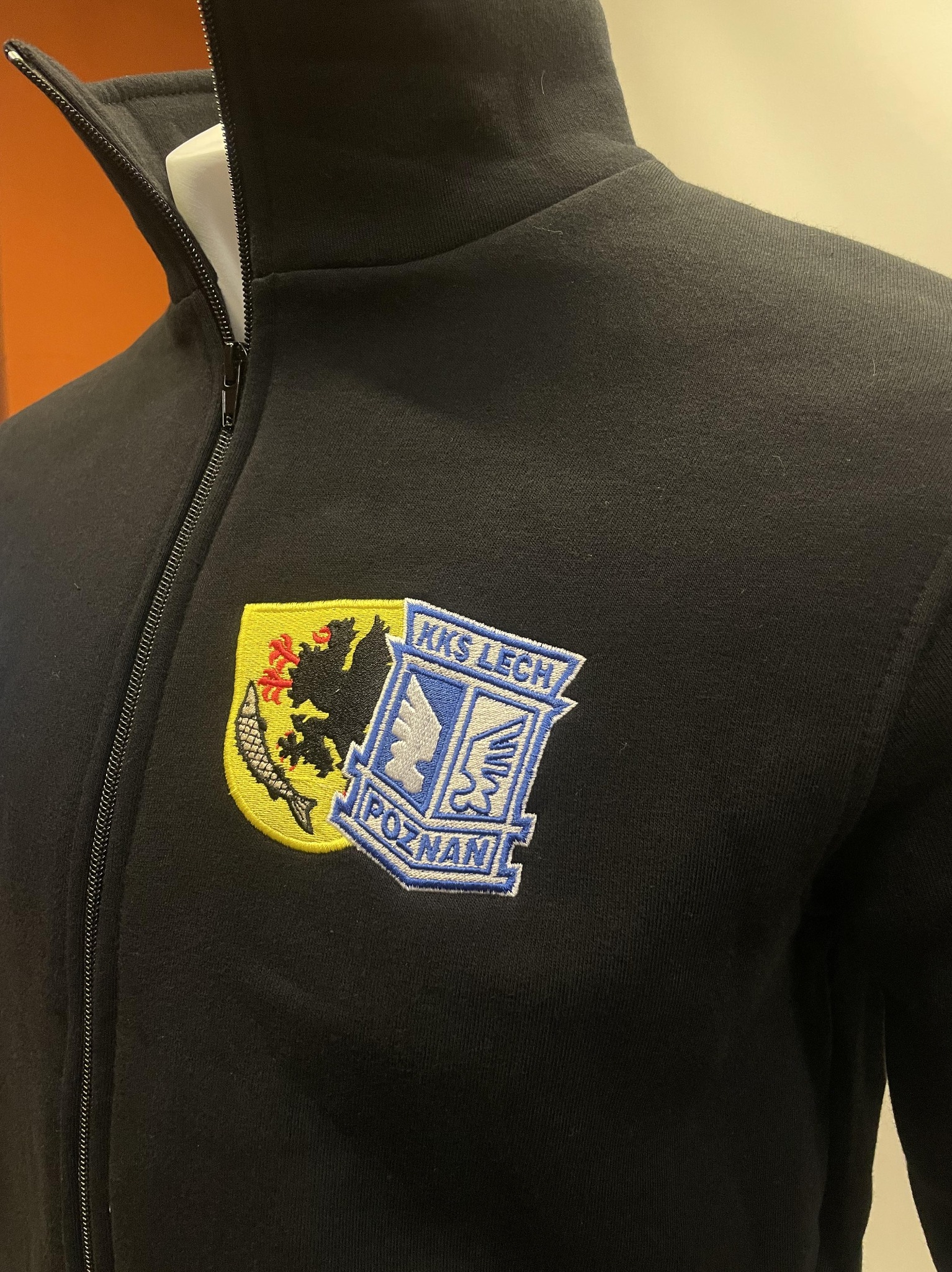 Czarna bluza sportowa rozpinana z haftowanym herbem klubu sportowego KKS Lech Poznań na piersi, prezentowana na manekinie.