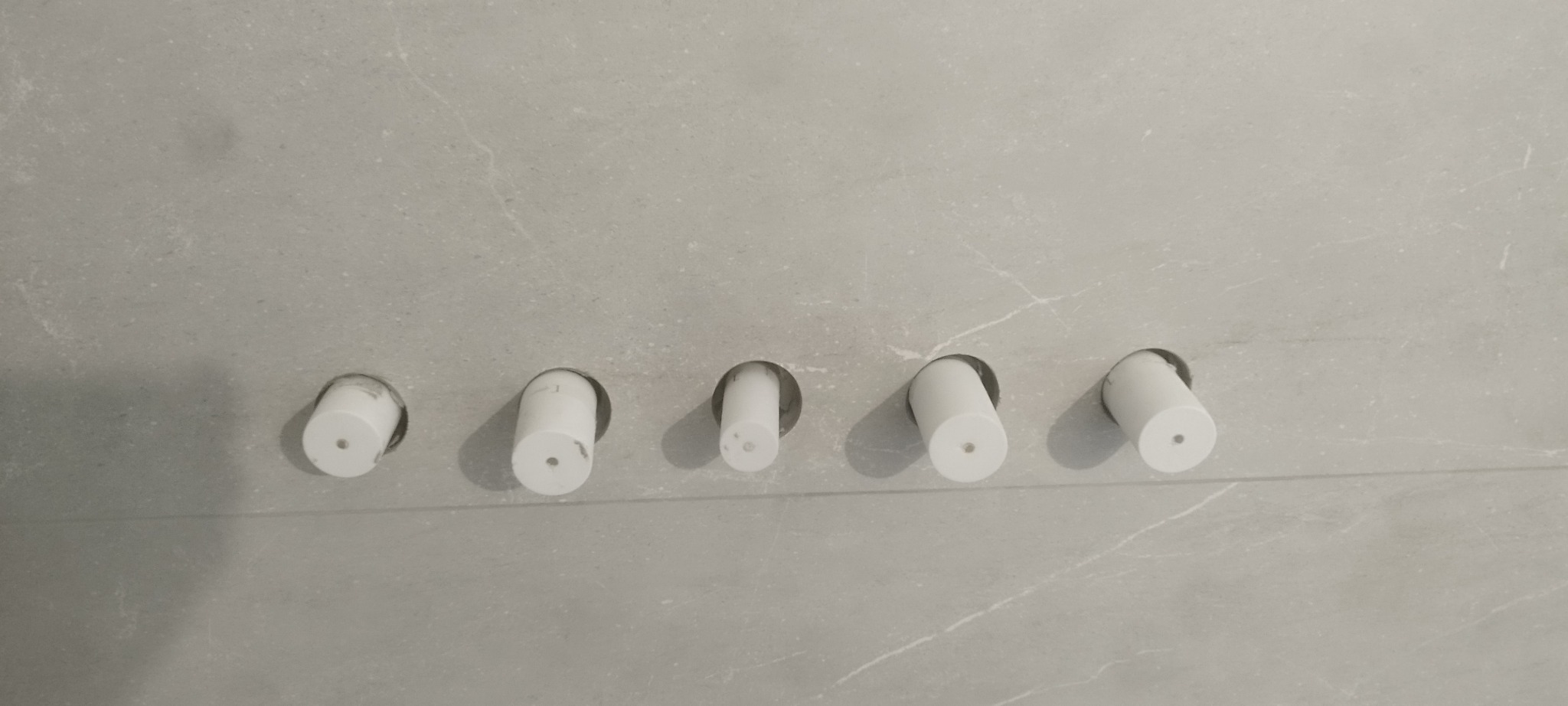 Szara ściana z marmurowym wzorem i wystającymi rurami instalacji wodnej w Świętochowie. Przygotowanie do montażu armatury łazienkowej.