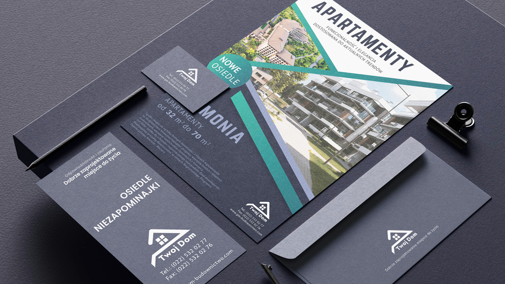 Zestaw materiałów firmowych, w tym wizytówka, ulotka reklamowa z wizualizacją osiedla apartamentów, koperta i ołówek, ułożone na ciemnoszarym tle.